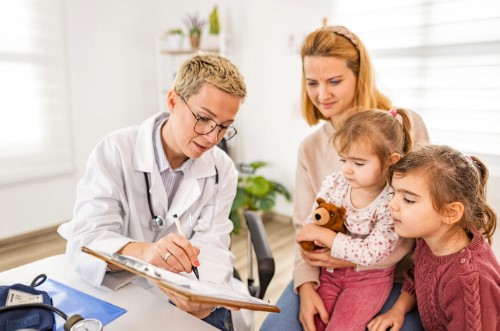 doctor showing clipboard to mother and children